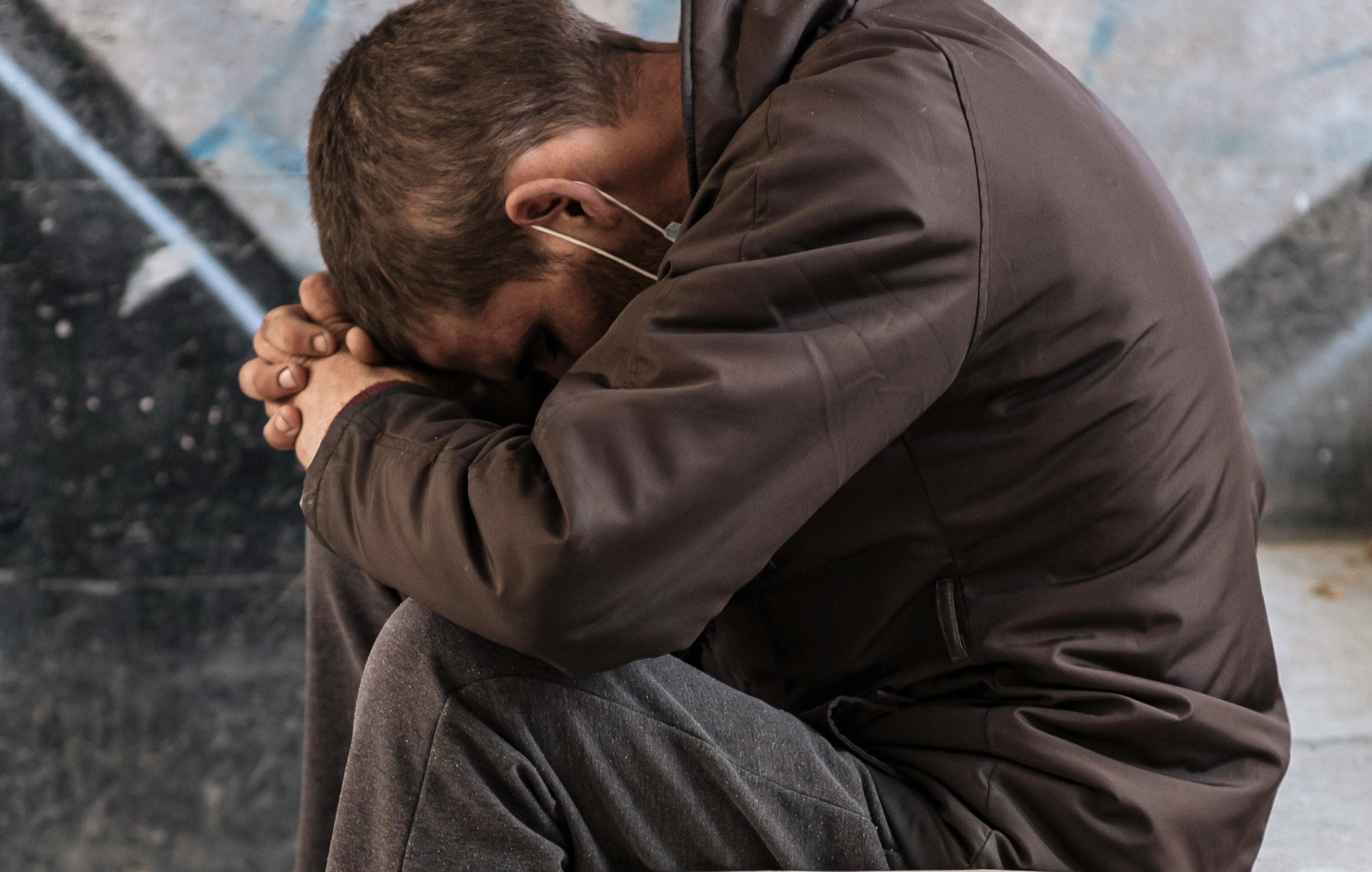 Homeless youth sits with cup and help sign